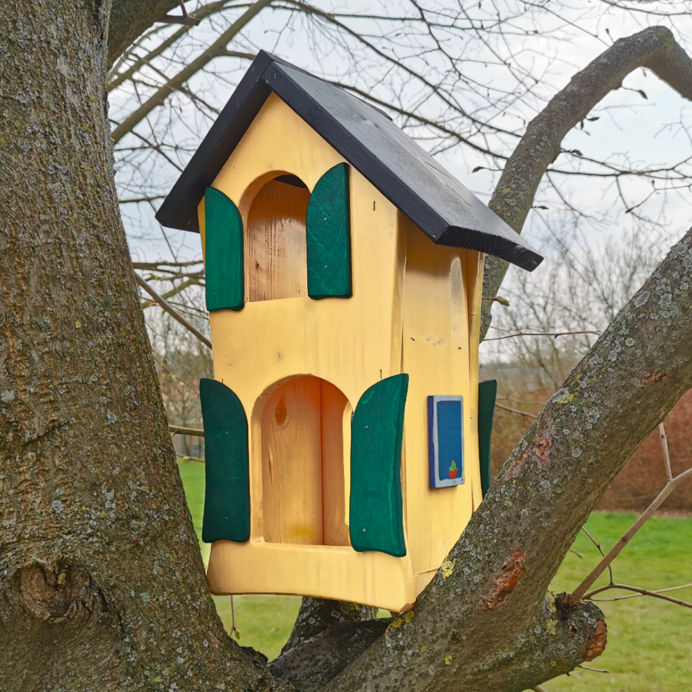 gelbes Vogelhäusschen auf einem Baum montiert
