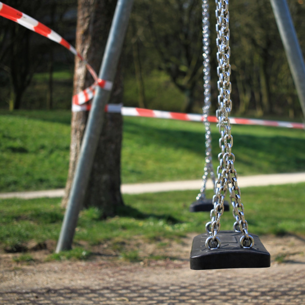 rot / weißes Absperrband sperrt Spielplatzschaukel ab