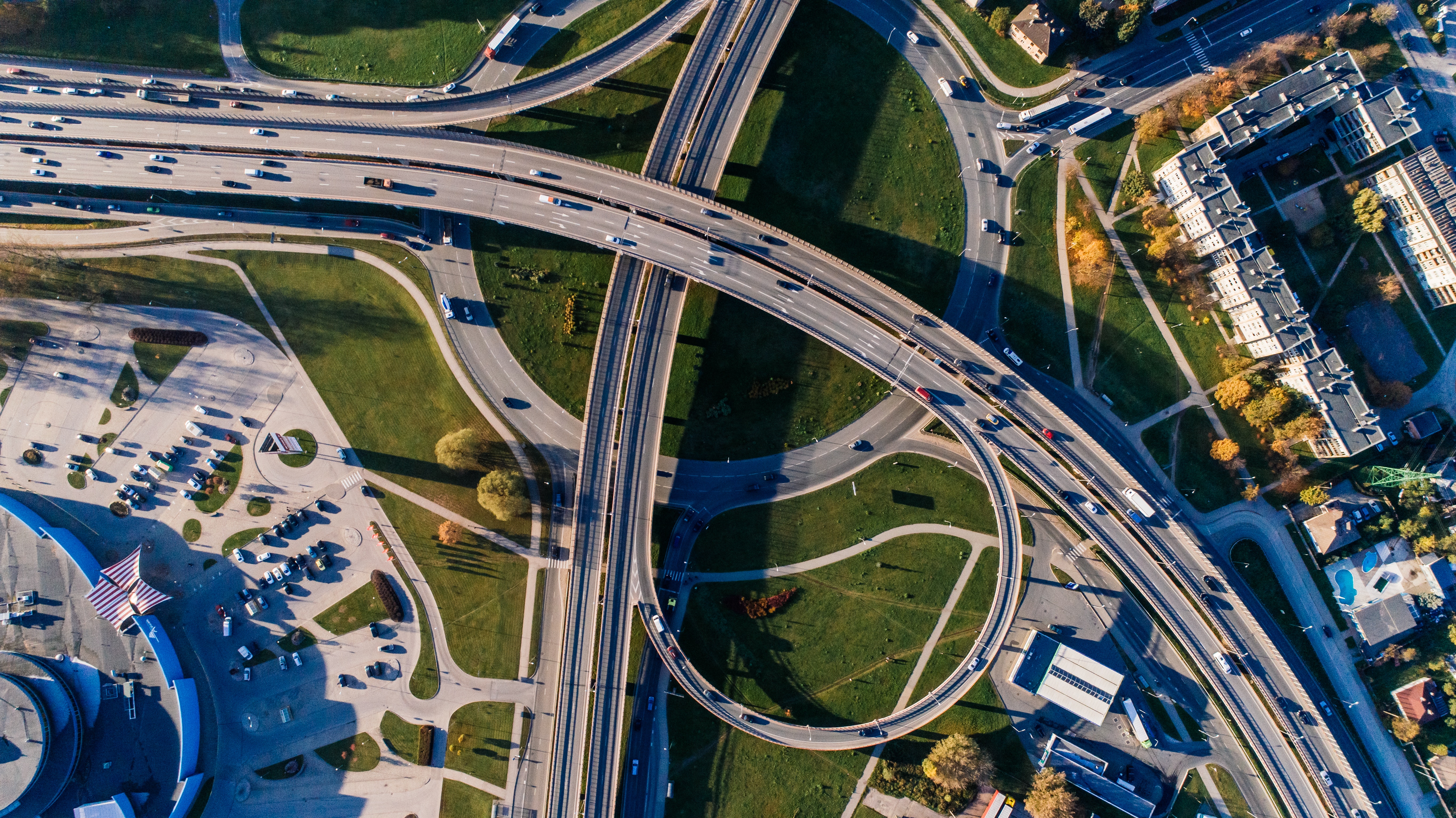 TERRAM Geotextilien Luftaufnahme einer vielspurigen Autobahn mit mehreren Überführungen und Abfahrten, umgeben von Grünflächen und Parkplätzen.