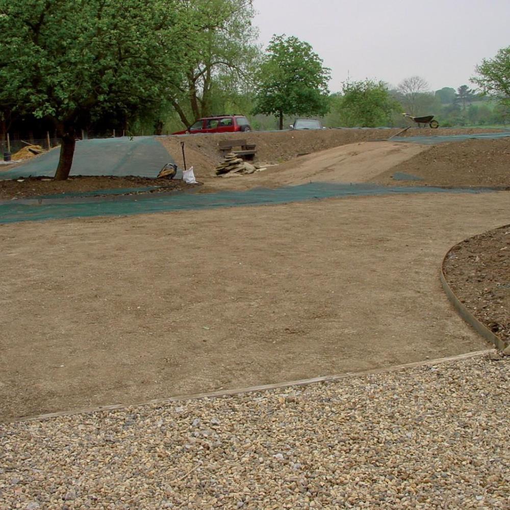braune Kiesfläche mit Sandfläche im Hintergrund