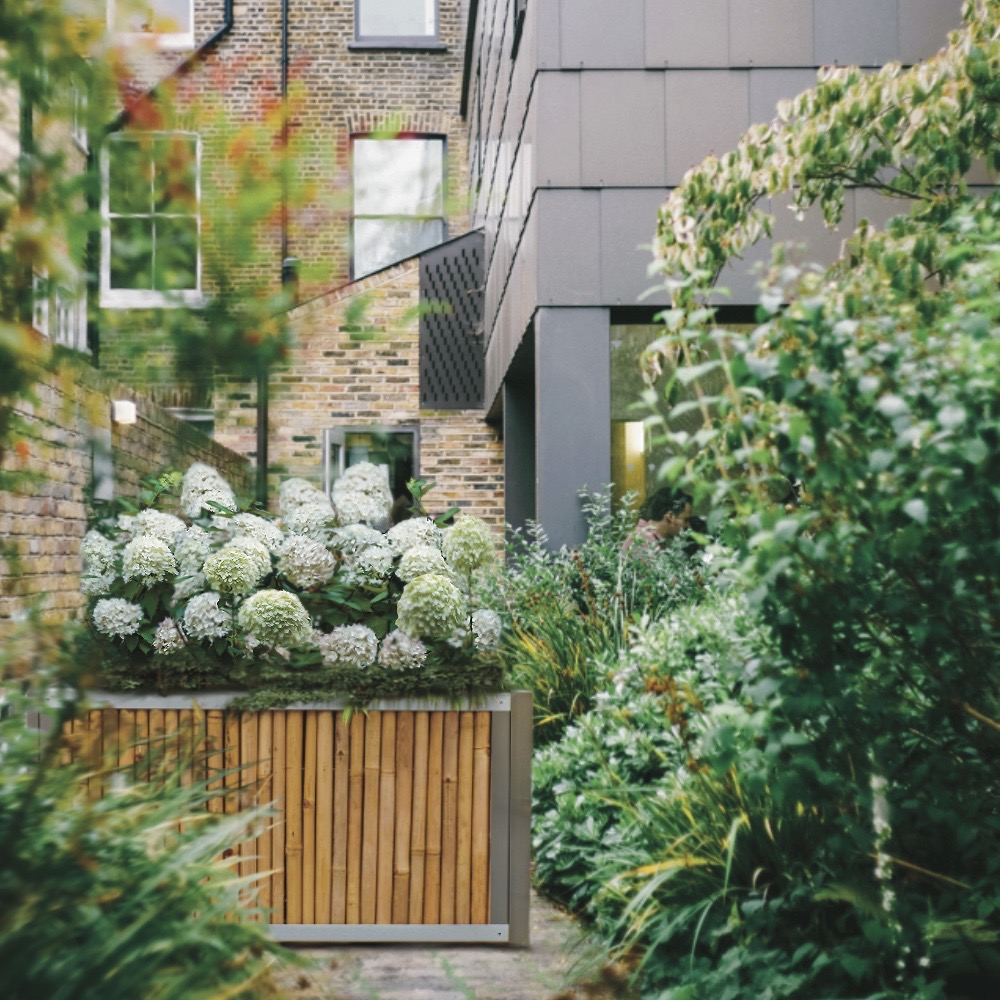 Hochbeet aus Edelstahl mit Seiten aus Bambus, bepflanzt im Stadtgarten