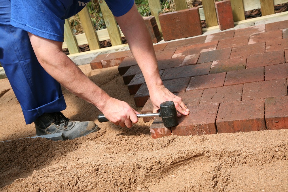 Pflastersteine werden auf Bettungsschicht gelegt