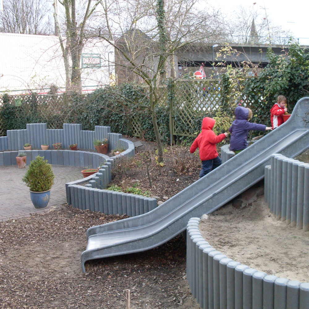 graue Hohlkehlpalisaden auf Spielplatz zum Abgrenzen von Sand