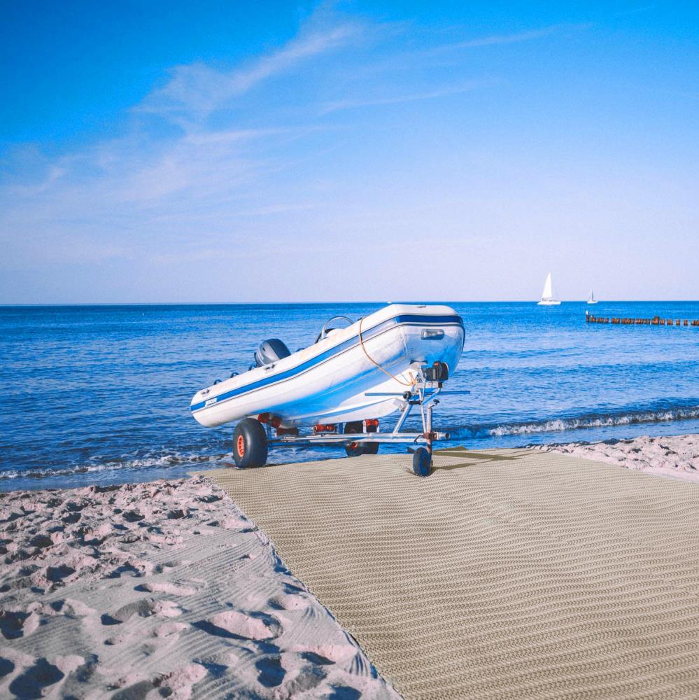 Sandmatte als Bootsslip mit Boot auf Hänger kurz vorm Wasser.