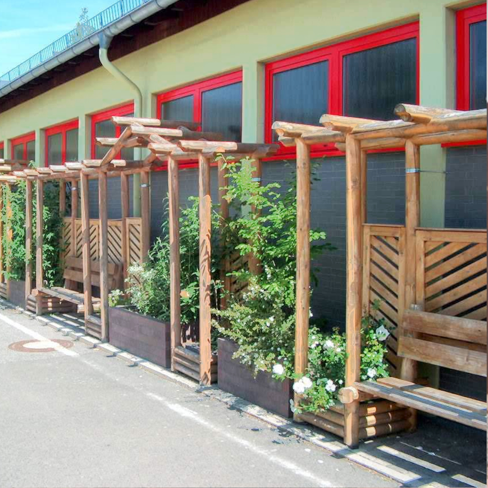 Holzsitzreihe mit 2 dunkelbraunen Hochbeeten mit Kletterpflanzen bepflanzt vor Hauswand