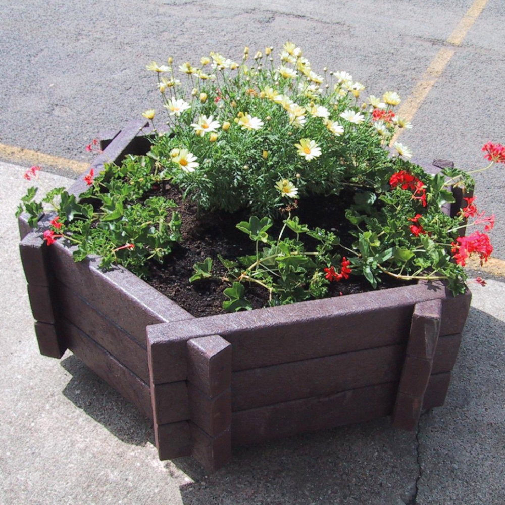 secheckiger Blumenkübel mit Bepflanzung auf Gehweg