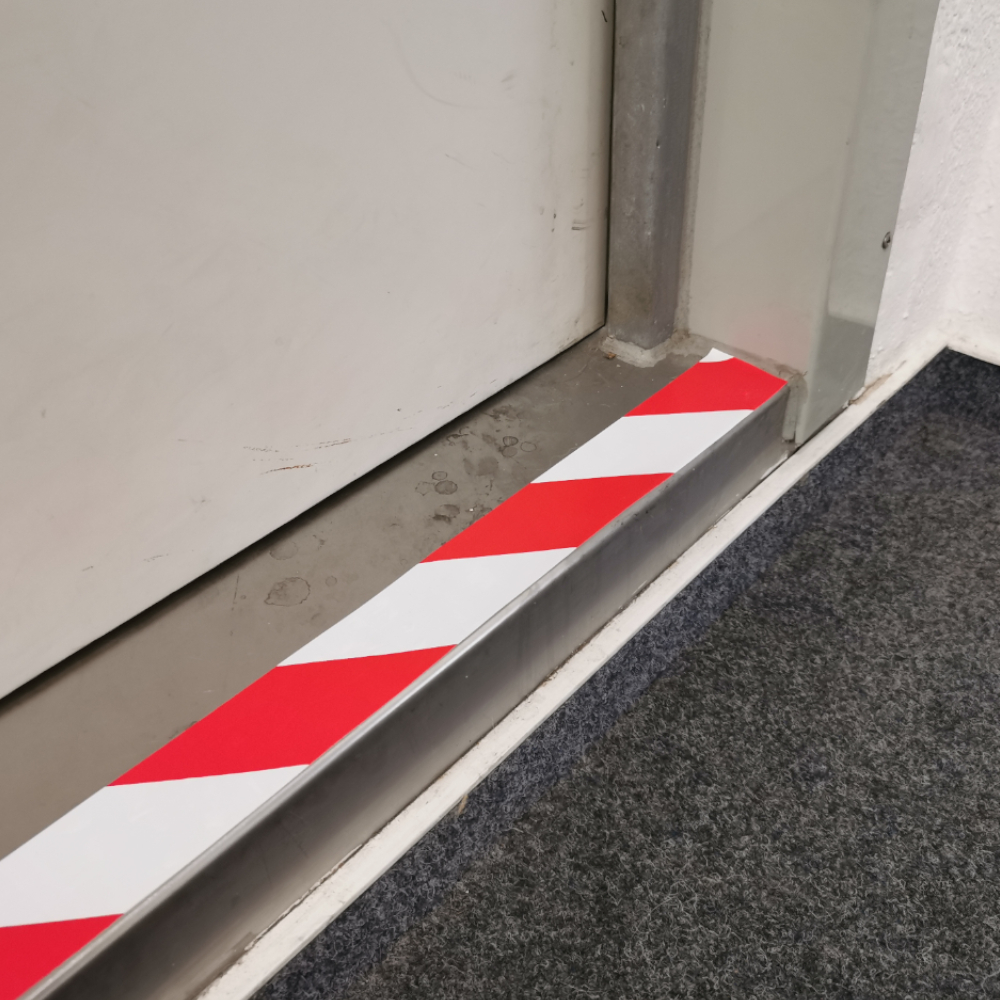 Warnmarkierung an Stolperfalle vor einer Tür